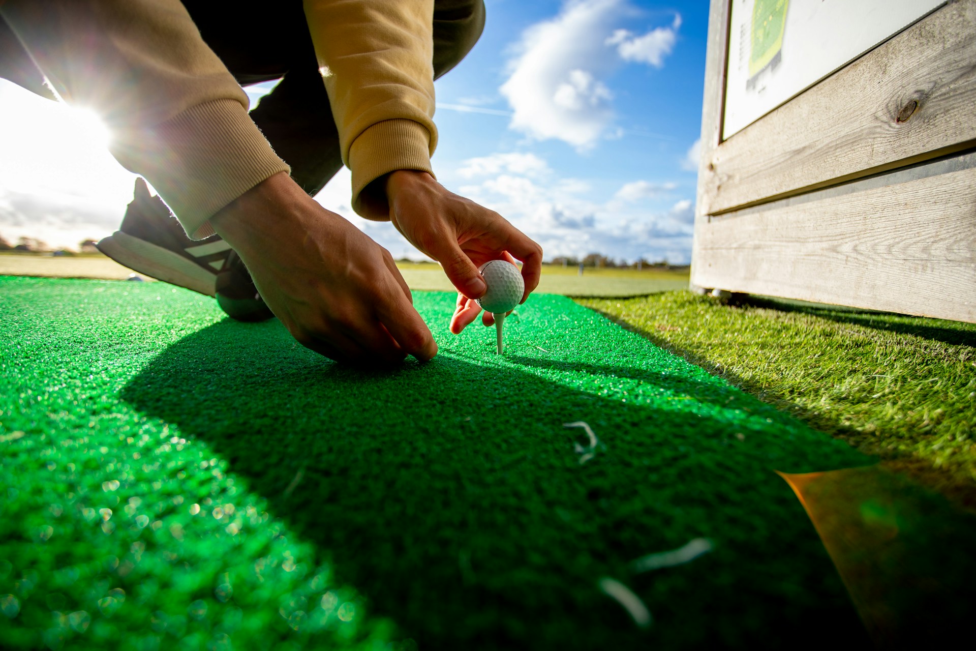 Golfer placing ball on tee at a driving range