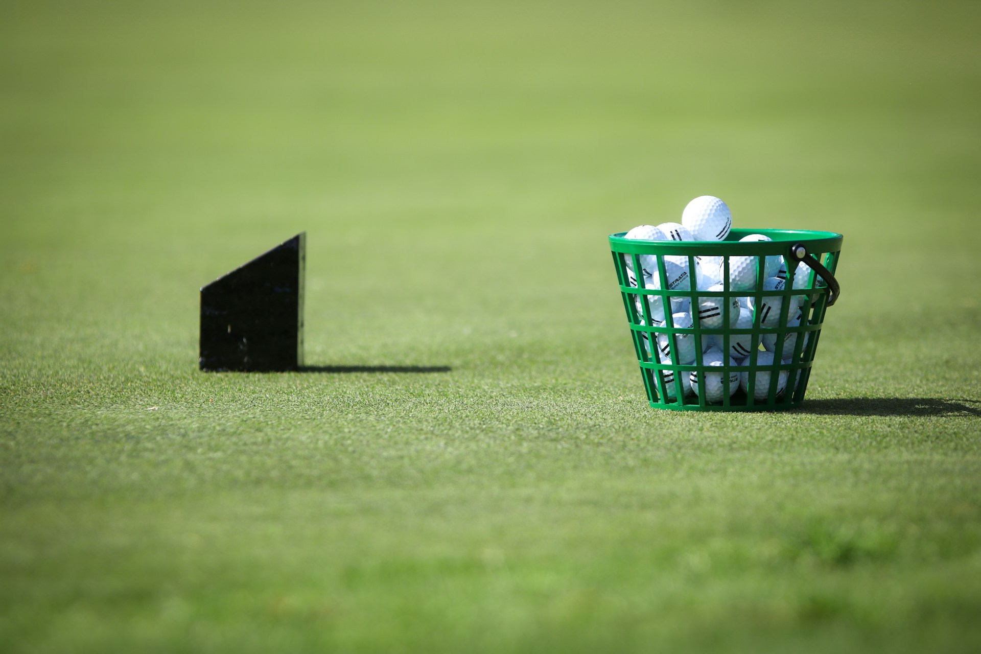 Practice balls on a putting green beside a hole marker